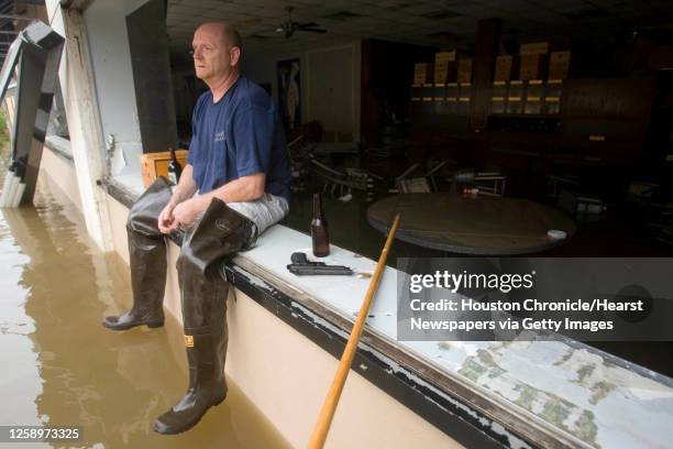 Brian Merrell sits on the window ledge of Rudy and Paco Restaurant keeping watch over the business that lost it windows and was flooded in the...