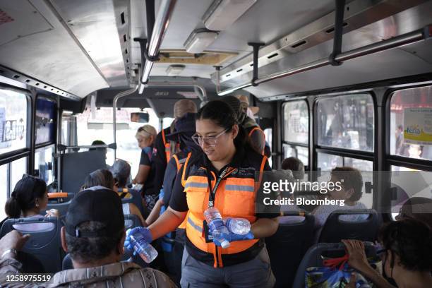 Worker hands out water bottles to bus passengers outside Mercado Juarez during a heat wave in Monterrey, Nuevo Leon state, Mexico, on Thursday, June...