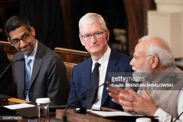 Google CEO Sundar Pichai and Apple CEO Tim Cook look on as India's Prime Minister Narendra Modi speaks during a meeting with senior officials and...