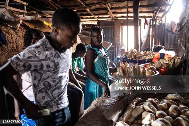 People gather to buy freshly baked bread inside Kroo Bay Slum in Freetown on June 23, 2023. Sierra Leoneans will vote in a general election on June...