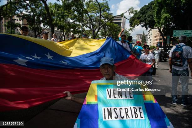 Demonstrators hold the Venezuelan flag during a rally to support opposition leader Maria Corina Machado on June 23, 2023 in Caracas, Venezuela. The...