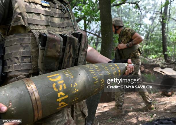 Ukrainian artilleryman carries a 155 mm shell to fire a M777 howitzer toward Russian positions near Avdiivka in the Donetsk region on June 23 amid...