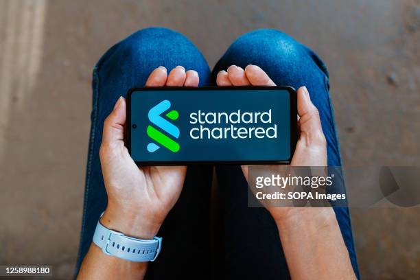 In this photo illustration, the Standard Chartered logo is displayed on a smartphone mobile screen.