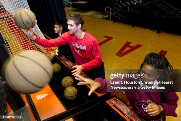 Houston Rockets forward Chandler Parsons, center, plays Pop-A-Shot with Luis Torres, left, and Laurin Sims, students at Young Women's and Men's...