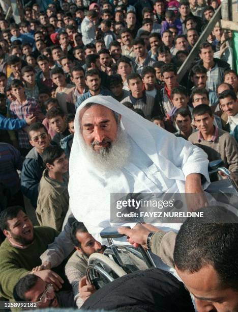 Sheikh Ahmed Yassin, spiritual leader of the Islamic Resistance Movement is is lifted onto the main stage of a HAMAS rally to mark the group's 11th...