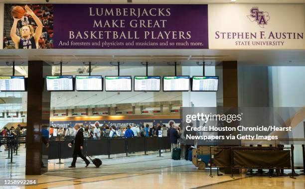 Airport patrons walk pas an advertisement for Stephen F. Austin State University in the terminal at Hobby Airport Tuesday, June 3 in Houston. This is...