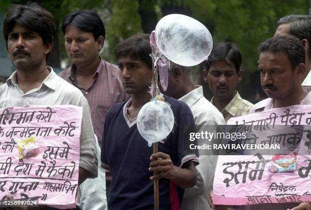 Activists affiliated to the opposition Congress Party display placards and inflated condoms during a demonstration against unemployement near...