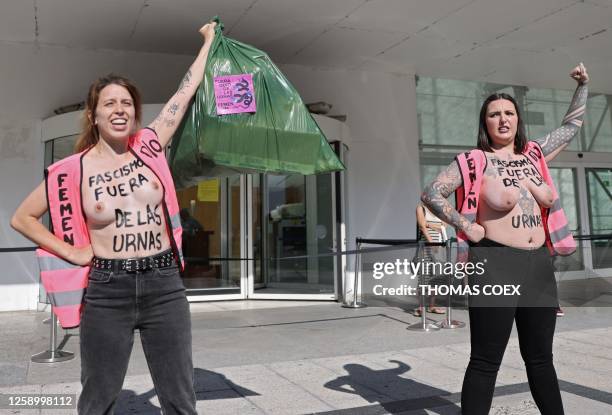 Femen activists with "Fascim out of the ballot boxes" written on their chest and holding trashbags protest in front of the venue where the Spanish...