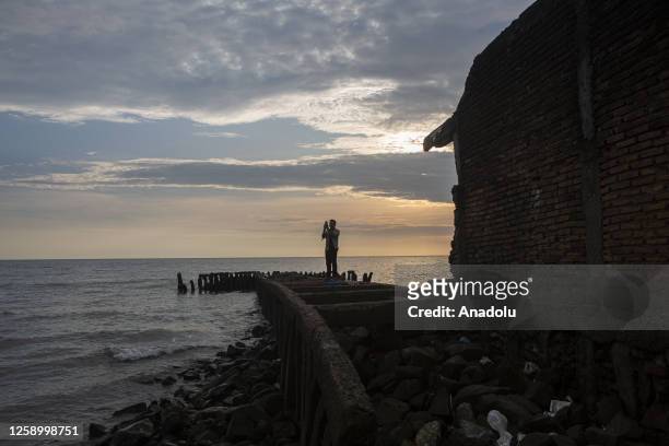 Man walk at a coastal village affected by rising sea level in Galesong, Takalar Regency, Indonesia, on June 20. Coastal abrasion due to the crashing...
