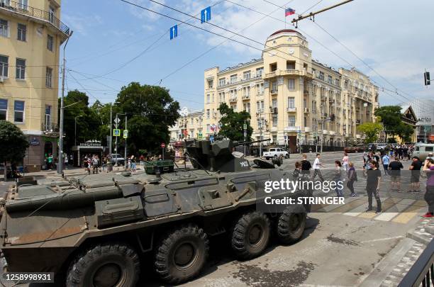 People walk past an armoured personnel carrier in the city of Rostov-on-Don, on June 24, 2023. President Vladimir Putin on June 24, 2023 said an...