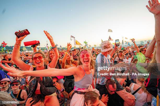 Crowds sing along and dance on shoulders watching Fred Again on the Other Stage as the sun sets over the Glastonbury Festival at Worthy Farm in...