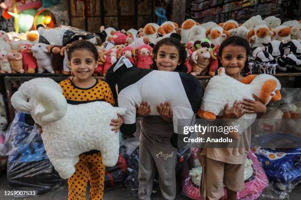 Girls hold fluffy plush toys in front of a toy stand at the market place before the upcoming Eid al-Adha in Gaza City, Gaza on June 24, 2023.