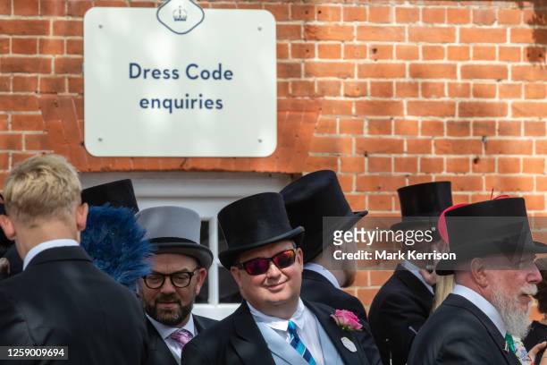 Racegoers in top hats are pictured in front of a Dress Code enquiries sign on the fifth day of Royal Ascot on 24 June 2023 in Ascot, United Kingdom....