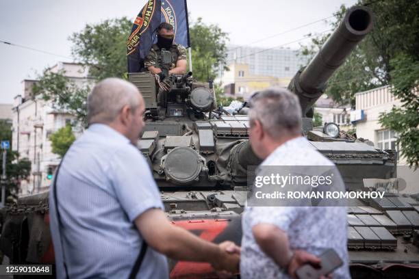 Member of Wagner group sits atop of a tank as two men shake hands in a street in the city of Rostov-on-Don, on June 24, 2023. President Vladimir...