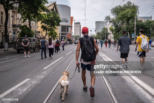 Man walks with his dog as members of the Wagner group patrol in the city centre of Rostov-on-Don, on June 24, 2023. President Vladimir Putin on June...