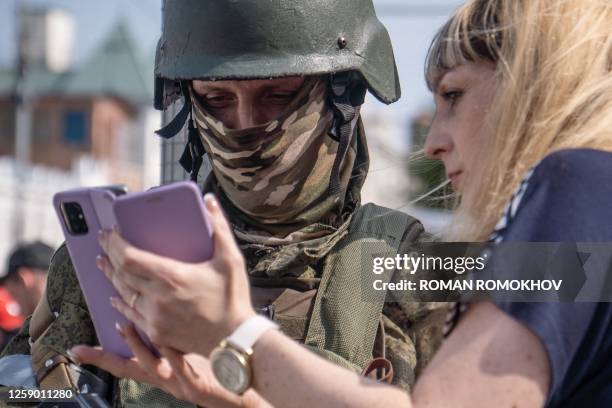 Woman shows her mobile phone as she speaks with a member of the Wagner group in the city of Rostov-on-Don, on June 24, 2023. President Vladimir Putin...