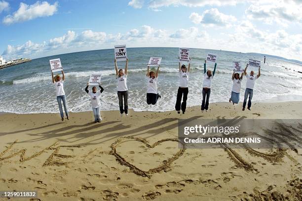 Local college students, supporters of Tony Blair, jump beside their message in the sand beneath The International Conference Centre during the Labour...