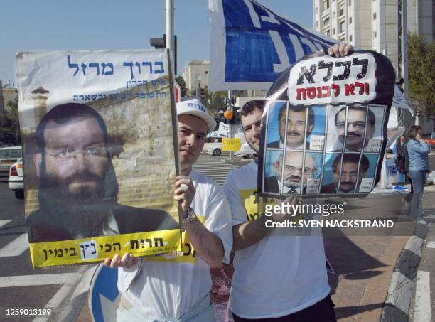 Activists from Israel's ultra-nationalist Herut party hold a poster of the party's number two candidate Baruch Marzel and another poster calling for...