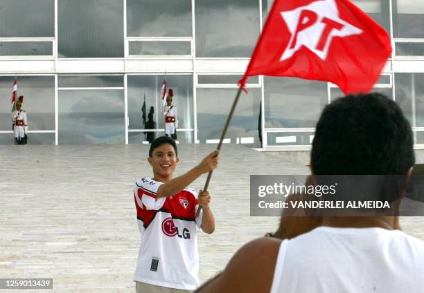 Man takes a picture of his son with the flag of the Workers Party, in front of the Planalto Palace in Brasilia, 30 December 2002. Un hombre toma una...