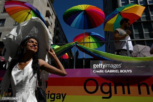 Participant poses in front of rainbow-coloured umbrellas during the annual Pride Parade to show support for members of the LGBT community, in Milan...