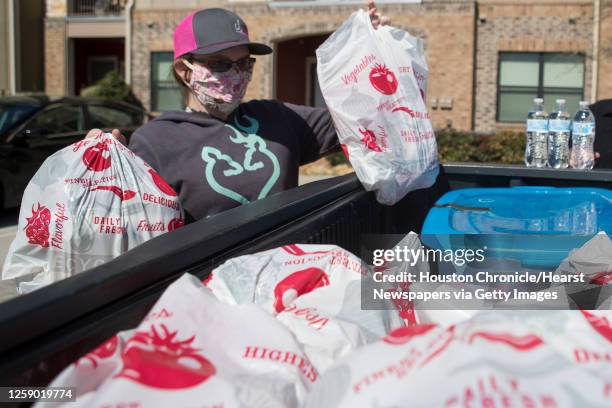 Maysi Whiteker grabs food bags out of the back of a truck as she helps make food and water deliveries with Crowdsource Rescue to families in need...