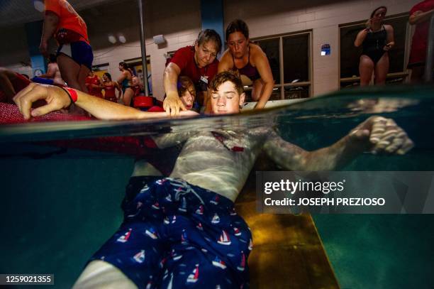 Youth lifeguards take part in a Swimposium where they practice skills to save people in the water in Waltham, Massachusetts on June 24, 2023. The...