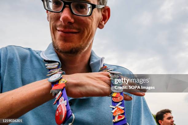 Participant shows a strap full of badges from various countries which he exchanged with other athletes as he visits the street party for athletes and...