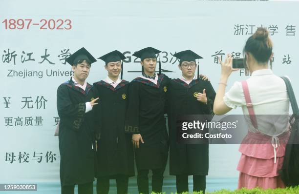 Students attending the graduation ceremony pose for a group photo in front of a large piece of high-speed train tickets on the campus of Zhejiang...