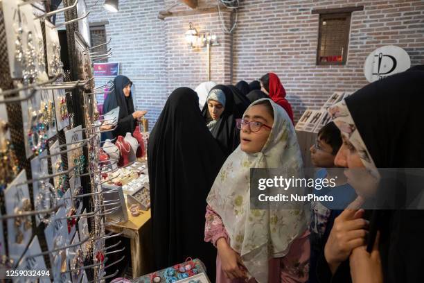 Young Iranian woman wearing a colorful dress and a headscarf looks at jewelries while visiting the first women's fashion and clothing exhibition, in...