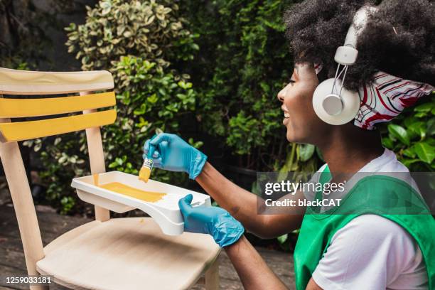 african american woman is painting a chair at home - backyard renovation stock pictures, royalty-free photos & images