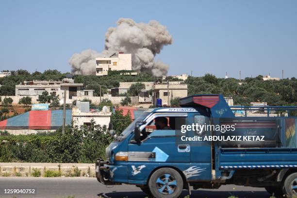 Truck drives on a road as a plume of smoke rises from a building during a reported Russian air strike on Syria's northwestern rebel-held Idlib...