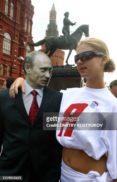 Teenage girl poses with a cardboard cutout of Russian President Vladimir Putin at rally of the pro-Kremlin youth group "Young Guard" just outside Red...