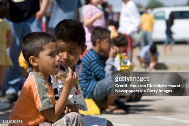 Luis Josue Villareal and his cousin Aaron Rogelio Paredes eat potatoe chips as their family waits in line at the Salvation Army's Pasadena location...
