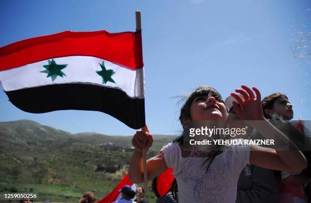 Druze girl waves a Syrian flag during a rally marking the Syrian Independence day in the Israeli-occupied Druze Golan Heights village of Majdel Shams...