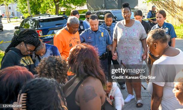 Kansas City Police Sgt. Jake Becchina andChief Stacey Graves gathered with people including Pat Clarke and Cherron Barney in the street to pray after...