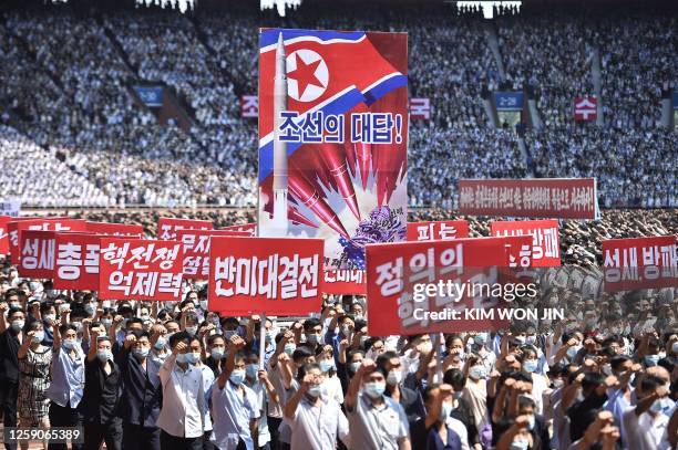 In this photo taken on June 25 residents of Pyongyang hold banners that read "answer of DPRK", "nuclear war deterrent", "anti-US confrontation" and...