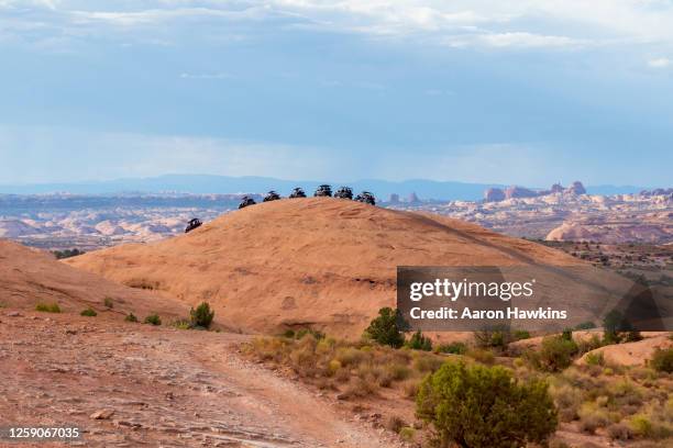 lijn van off road side by side vehicles op sandstone summit in hell's revenge area in de buurt van moab utah - atv trail stockfoto's en -beelden