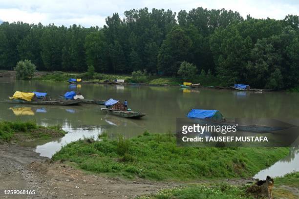 Man stands on a sand boat at river Jhelum in the outskirts of Srinagar on June 26, 2023.