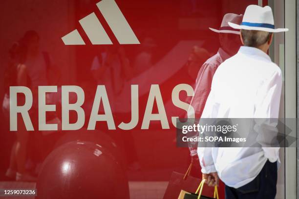 Man walks past an Adidas logo on Rebajas store on Calle Preciados in Madrid. On Friday, June 21, the large stores and shops in Madrid have kicked off...