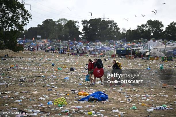 Festival goers carry their belongings as they walk across a field covered in litter at the end of Glastonbury festival in the village of Pilton in...