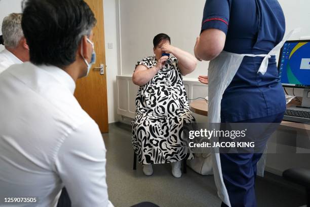 Britain's Prime Minister Rishi Sunak and Britain's Health Secretary Steve Barclay watch as a patient 'Susan' takes a Spirometry Test during a visit...