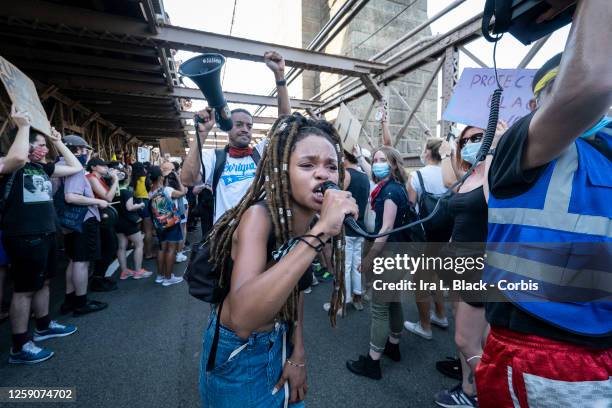 July 25: Livia Rose Johnson an organization leader of Warriors In the Garden holds her hand up and yells into a microphone as she leads the crowd of...