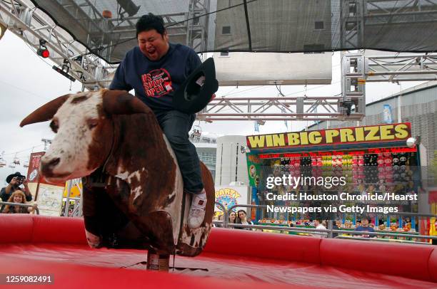 Japanese Sumo wrestler Takuji Noro who competes as "Noro" rides a mechanical bull during a tour of The Houston Livestock Show & Rodeo Wednesday,...