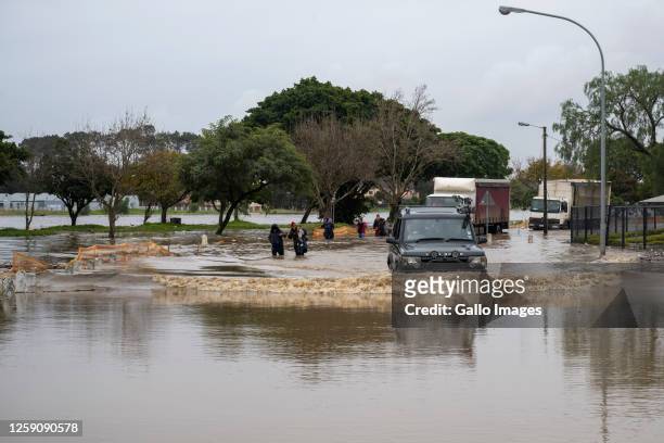 Pedestrians try to cross a flooded road at Oosboschstraat petrol station at the Agrimark on June 14, 2023 in Paarl, South Africa. It is reported that...