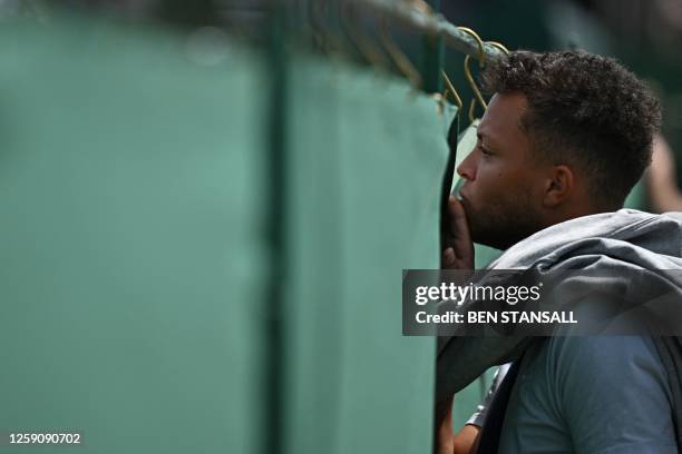 Spectator catches a view of matches being played on court during the Wimbledon qualifying tennis tournament in Roehampton in west London on June 26,...