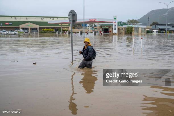 Pedestrians try to cross a flooded road at Oosboschstraat petrol station at the Agrimark on June 14, 2023 in Paarl, South Africa. It is reported that...