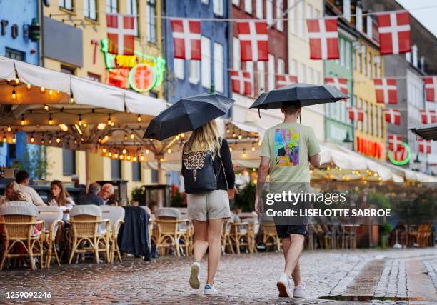 People use umbrellas to shelter from the rain in Copenhagen on June 26, 2023. / Denmark OUT