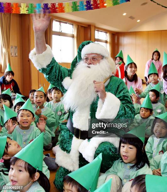 Santa Claus dressed in a green suit is surrounded by nursery school children as he gives out flower seeds at the Kozunomori nursery school in Narita...