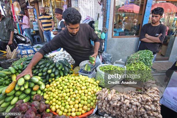 Vegetable vendor attends to a customer ahead of Eid al-Adha in Srinagar, Kashmir, India on June 26, 2023.