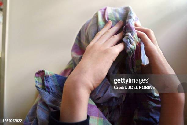 Un enfant autiste se voile le visage avec un drap, le 20 mai 2003, dans la salle de jeux de l'institut médico-éducatif "Notre Ecole" à Paris. Cet...